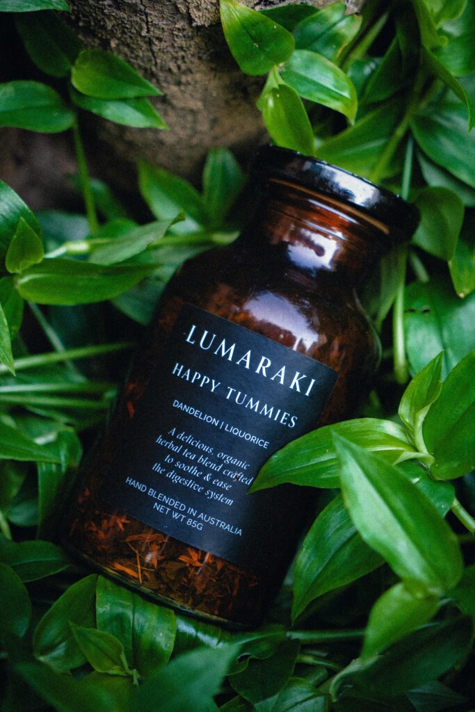 pexels-photo-19146885-19146885 Close-up of a Lumaraki herbal supplement bottle surrounded by lush green leaves.
